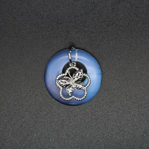 Vue détaillée de la breloque papillon en métal ajouré sur un pendentif en agate bleue.