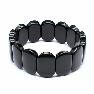 Close-up of polished black natural stone beads on a minimalist hand plate bracelet