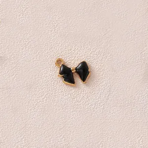 Nahaufnahme eines schwarz emaillierten vergoldeten Schleifenanhängers für DIY-Schmuck.