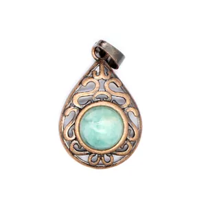 Macro close-up of a vintage teardrop pendant with hollow patterns and a green gemstone.