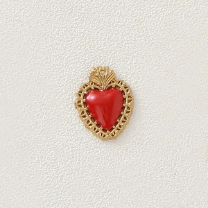 Dettaglio di un ciondolo a cuore dorato vintage con centro in smalto rosso acceso.