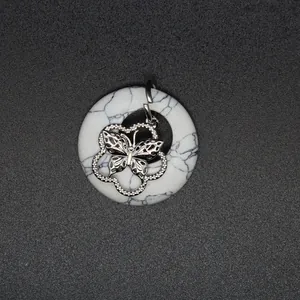 Vue rapprochée d'un pendentif en pierre blanche marbrée avec un charmant papillon argenté