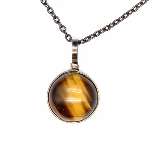 Close-up detail of a vintage round tiger's eye stone pendant necklace on a bronze chain.