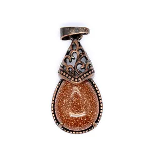 Close-up view of a vintage bronze teardrop pendant featuring sparkling goldstone