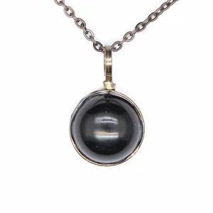 Macro detail of a vintage style necklace with a smooth round black onyx stone pendant