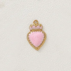Dettaglio del ciondolo a cuore placcato in oro con corona e smalto rosa stile vintage.