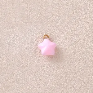 Nahaufnahme eines rosa Emaille-Sternanhängers mit vergoldeter Öse für DIY-Schmuck.