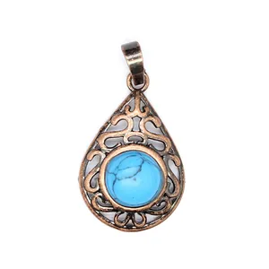 Macro detail of antique copper filigree pendant with turquoise stone inlay.