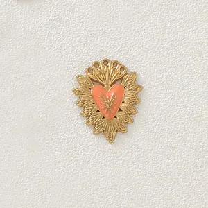 Dettaglio di un ciondolo a cuore vintage placcato oro con smalto arancione brillante.