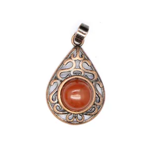 Close-up of a vintage bronze hollow-out teardrop pendant with a red aventurine stone center