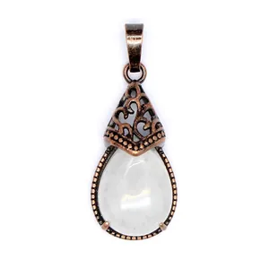 Macro view of vintage teardrop pendant with milky white stone and antique copper filigree