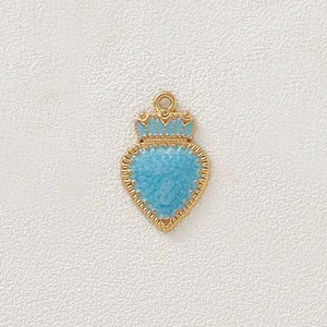 Dettaglio di un ciondolo a cuore con corona placcato in oro e smalto azzurro