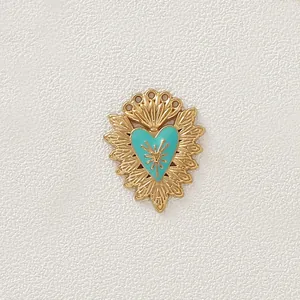 Primo piano di un ciondolo a cuore in acciaio inossidabile dorato con dettagli in smalto blu.