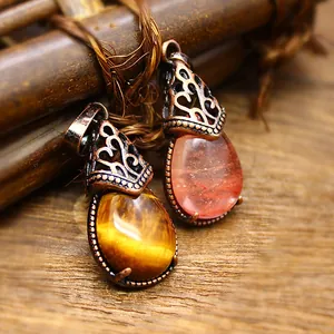 Pair of vintage teardrop natural stone pendants with bronze filigree caps on rustic wood