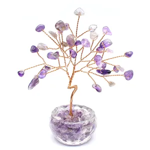 Close-up of handmade amethyst crystal money tree with copper wire on white background.