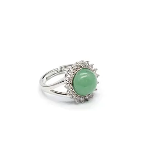Detail of silver adjustable ring with a green gemstone surrounded by white crystals
