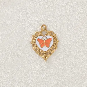 Primo piano del ciondolo a cuore in acciaio inossidabile placcato oro con farfalla arancione.