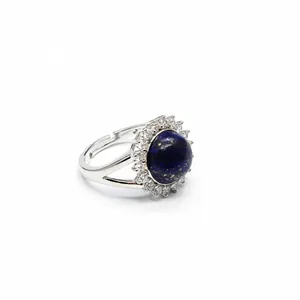 Detailed view of an adjustable silver ring with a round blue stone and crystal halo