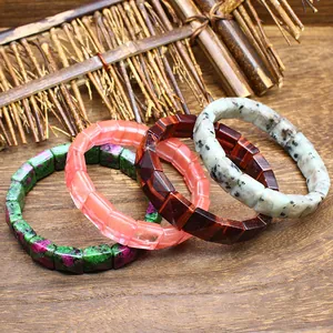 Close-up of four natural stone bracelets with faceted square beads on rustic wood