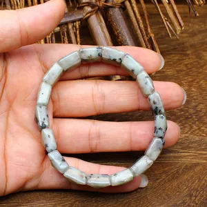 Close-up detail of a natural stone stretch bracelet with faceted square beads held on a hand