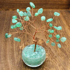 Close-up view of a handmade green crystal life tree ornament on a wooden surface.