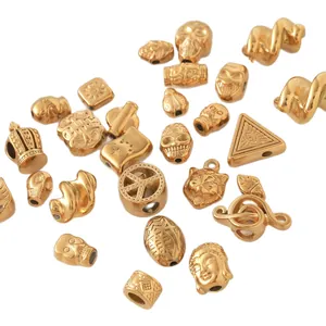 Collection of gold plated stainless steel beads for DIY jewelry with skulls and crown charms.