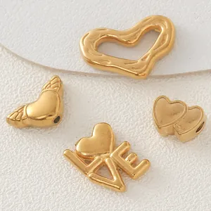 Dettaglio di ciondoli a cuore e LOVE in acciaio dorato per la creazione di gioielli