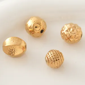 Gros plan de quatre perles décoratives en acier inoxydable doré aux textures uniques
