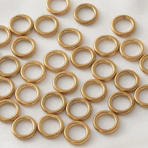 Close-up of gold-plated stainless steel seamless O-rings on white silk background