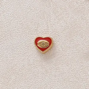 Red heart enamel pendant with a golden evil eye charm for DIY jewelry making projects