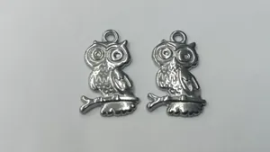 Detailed view of two silver stainless steel owl pendants for DIY jewelry making