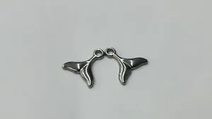 Detaillierte Nahaufnahme von polierten Walflossen-Anhängern aus Edelstahl für DIY-Schmuck