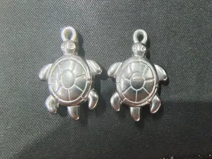 Detail von zwei silbernen Meeresschildkröten-Anhängern aus Edelstahl für DIY-Schmuck