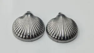 Close-up detail showing the ribbed texture of polished stainless steel shell charms