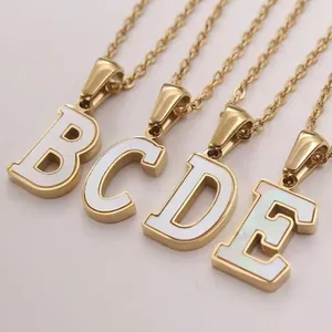 Detail shot of gold-plated necklaces with pearlescent shell alphabet pendants B to E