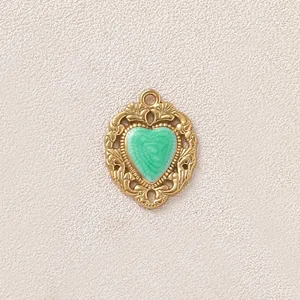 Primo piano del ciondolo a cuore vintage placcato oro con smalto verde e incisioni