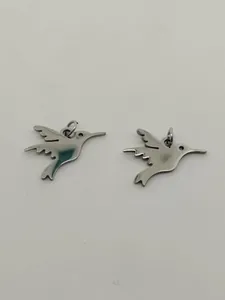 Detailed view of two polished stainless steel hummingbird pendants with jump rings