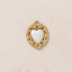 Dettaglio di un ciondolo a cuore dorato vintage con intarsio in smalto bianco craquelé