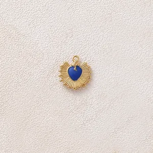 Primo piano del ciondolo a cuore dorato con centro in smalto blu e dettagli a raggi radiali