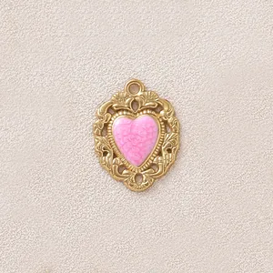 Vista dettagliata di un ciondolo a cuore vintage placcato oro con smalto rosa per DIY
