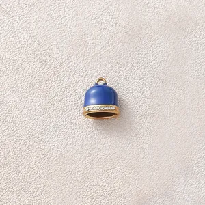 Close-up detail showing a blue enamel bell charm with gold plating and sparkling rhinestones.