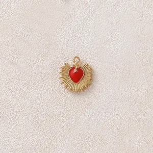Macro di un ciondolo a cuore in smalto rosso e acciaio inossidabile dorato con raggi solari