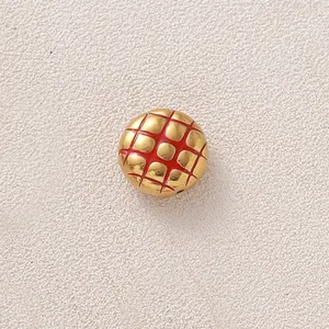 Nahaufnahme einer goldenen Edelstahlperle mit rotem Ananasbrötchen-Gittermuster