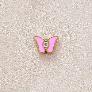 Pink enamel butterfly charm with gold plating and evil eye detail for DIY jewelry.