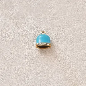 Detail view of a blue enamel bell pendant with gold plating and sparkling rhinestones.