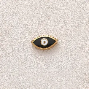 Detail macro of gold-plated stainless steel evil eye bead with black oil dripping.