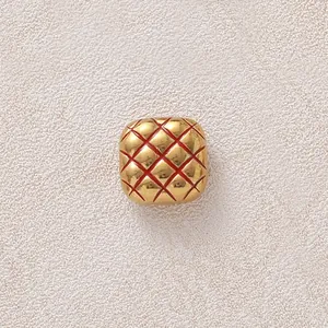Nahaufnahme einer vergoldeten Edelstahlperle mit rotem, gestepptem Ananasmuster-Detail.