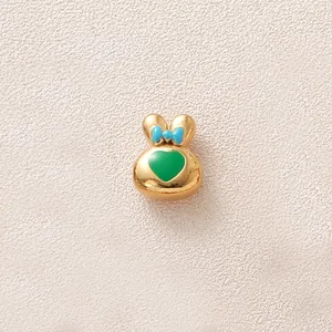 Gros plan d'une breloque lapin dorée avec nœud bleu et cœur vert pour la création de bijoux