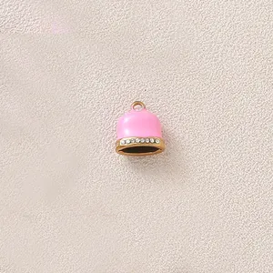 Detailed close-up of pink enamel bell pendant with gold plating and sparkling rhinestones