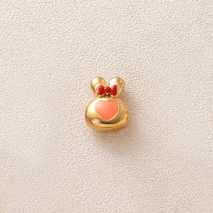 Vue détaillée d'une breloque lapin dorée avec nœud rouge et cœur rose